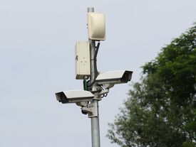 Un mât de deux caméras et une antenne, à la salle des sports. 