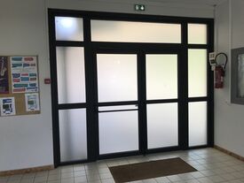 Nouvelle porte d'entrée du groupe scolaire, équipée d'un vitrage occultant et d'une barre de sortie antipanique.